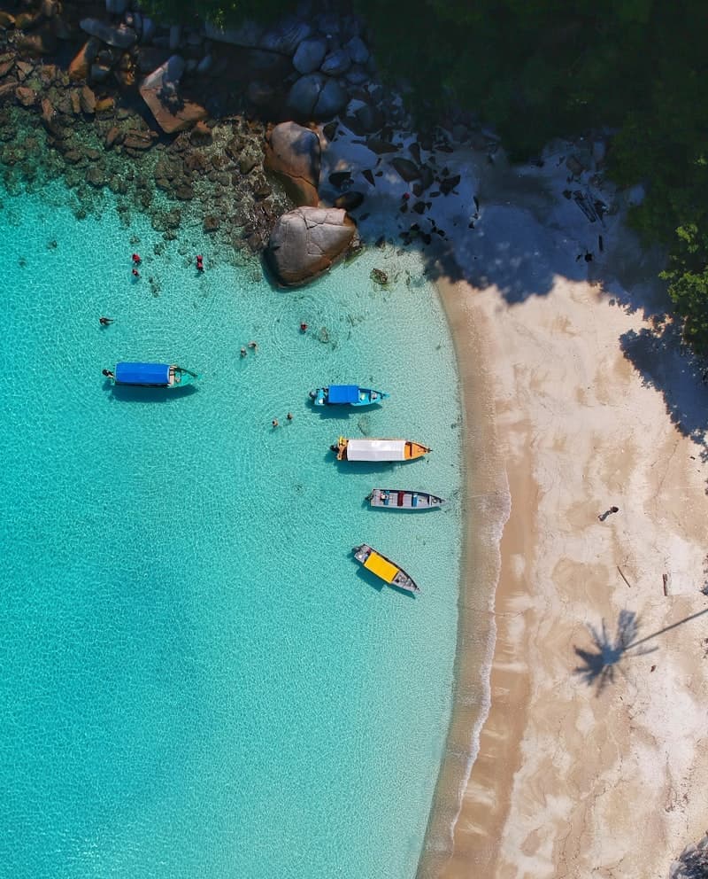 Vue aérienne d'une plage et de barques colorées sur un lagon turquoise