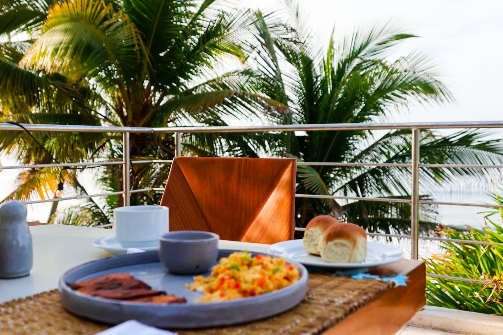 Petit-déjeuner servi sur la terrasse d'un hôtel, face aux palmiers et à l'océan